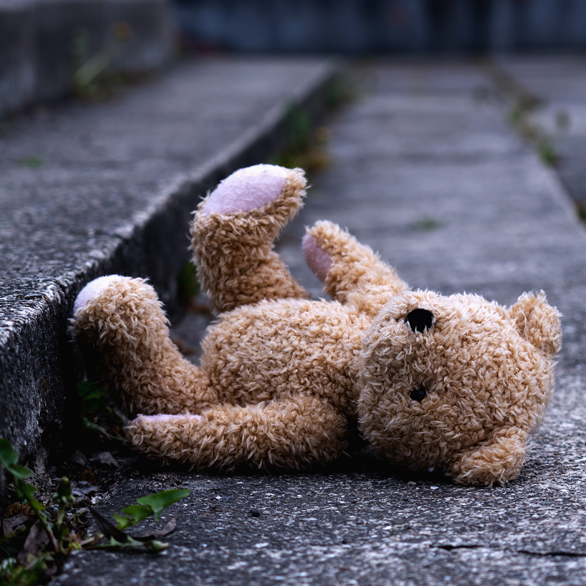 Ein Teddybär liegt auf einer Außentreppe aus Stein.