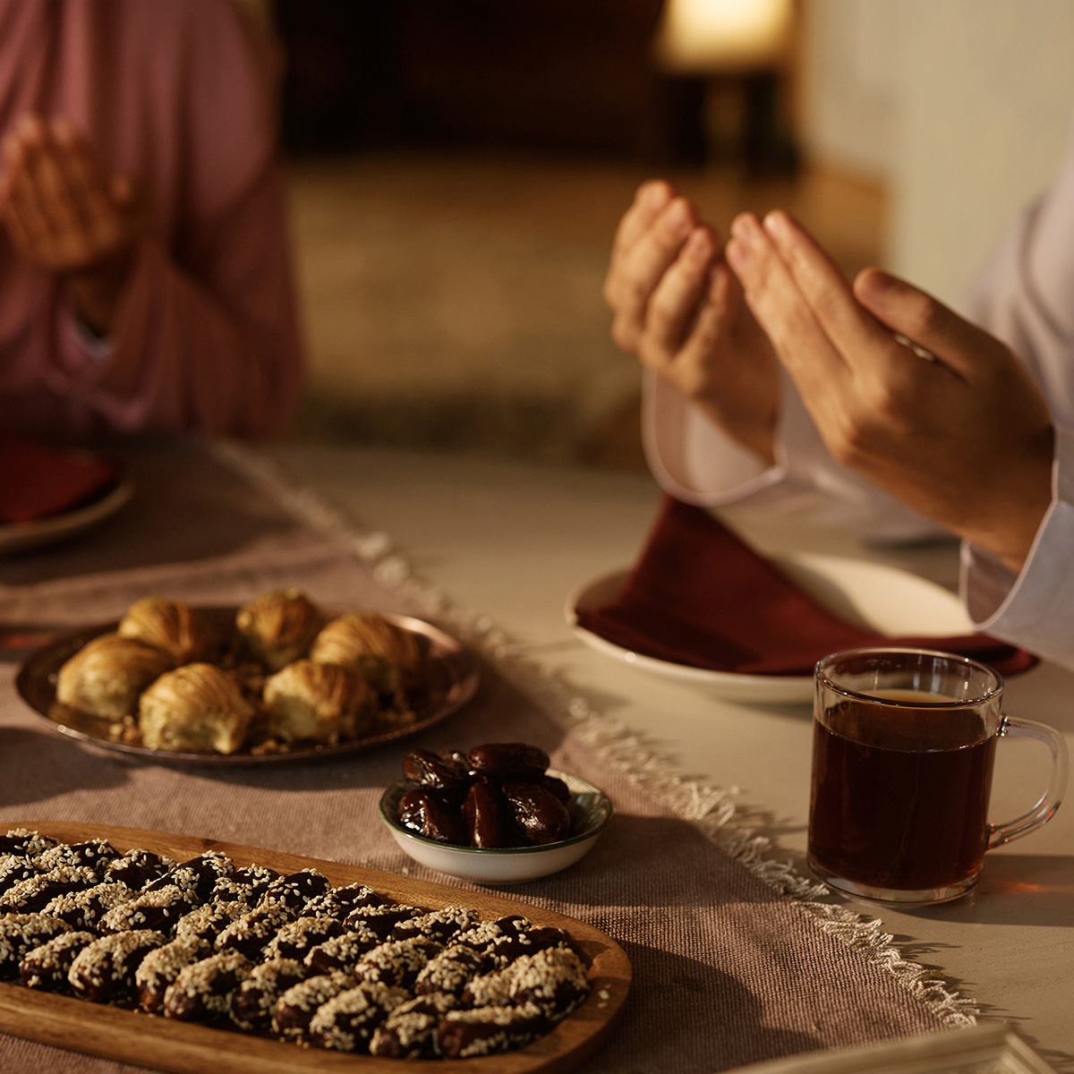 Zwei Menschen sitzen betend am gedeckten Tisch.