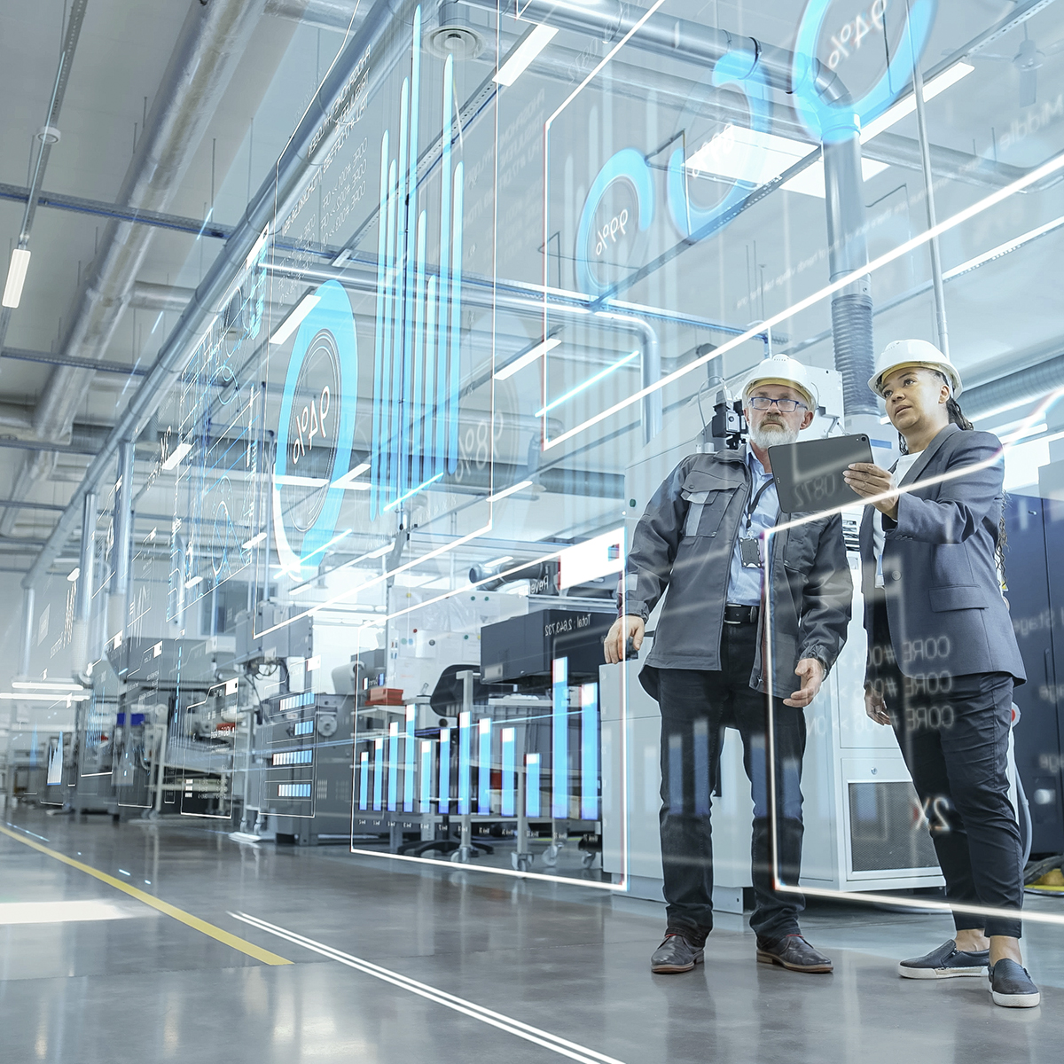 Zwei Menschen in einer Produktionshalle mit Tablet in der Hand.