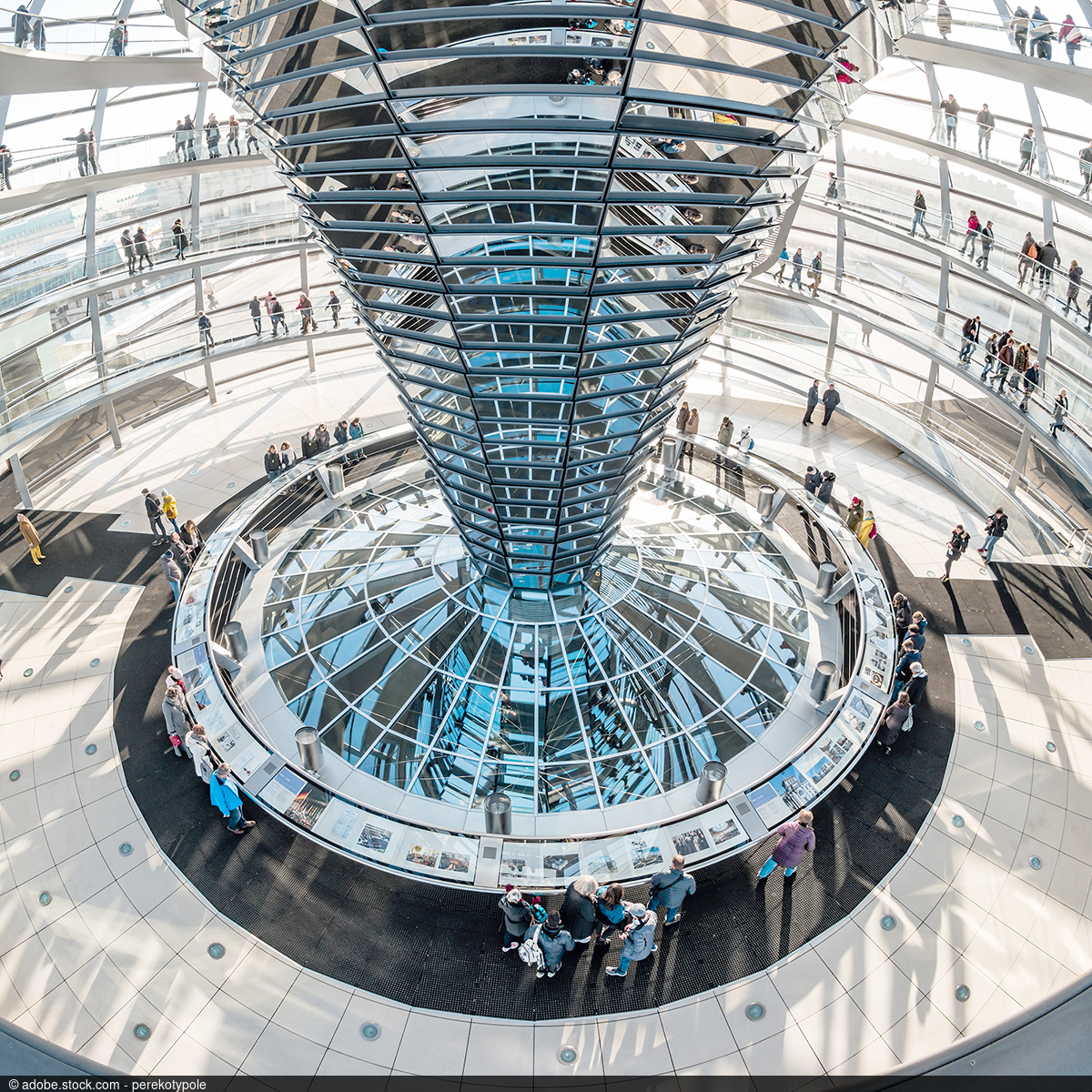 Innenansicht der gläsernen Reichstagskuppel in Berlin mit zentraler Spiegelkonstruktion und Besucherinnen und Besuchern auf den umlaufenden Rampen.