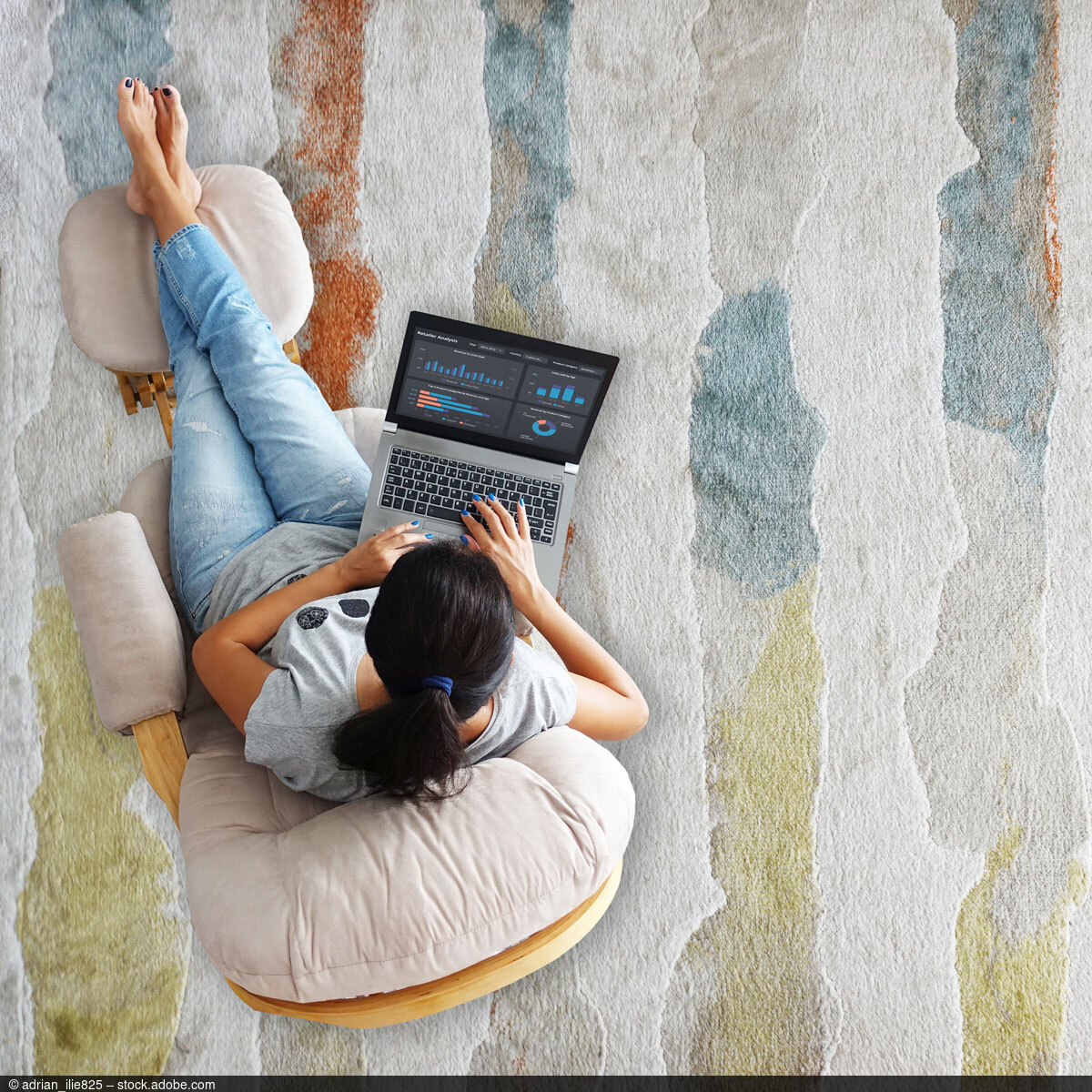 Frau sitzt in Sessel mit Laptop auf dem Schoß