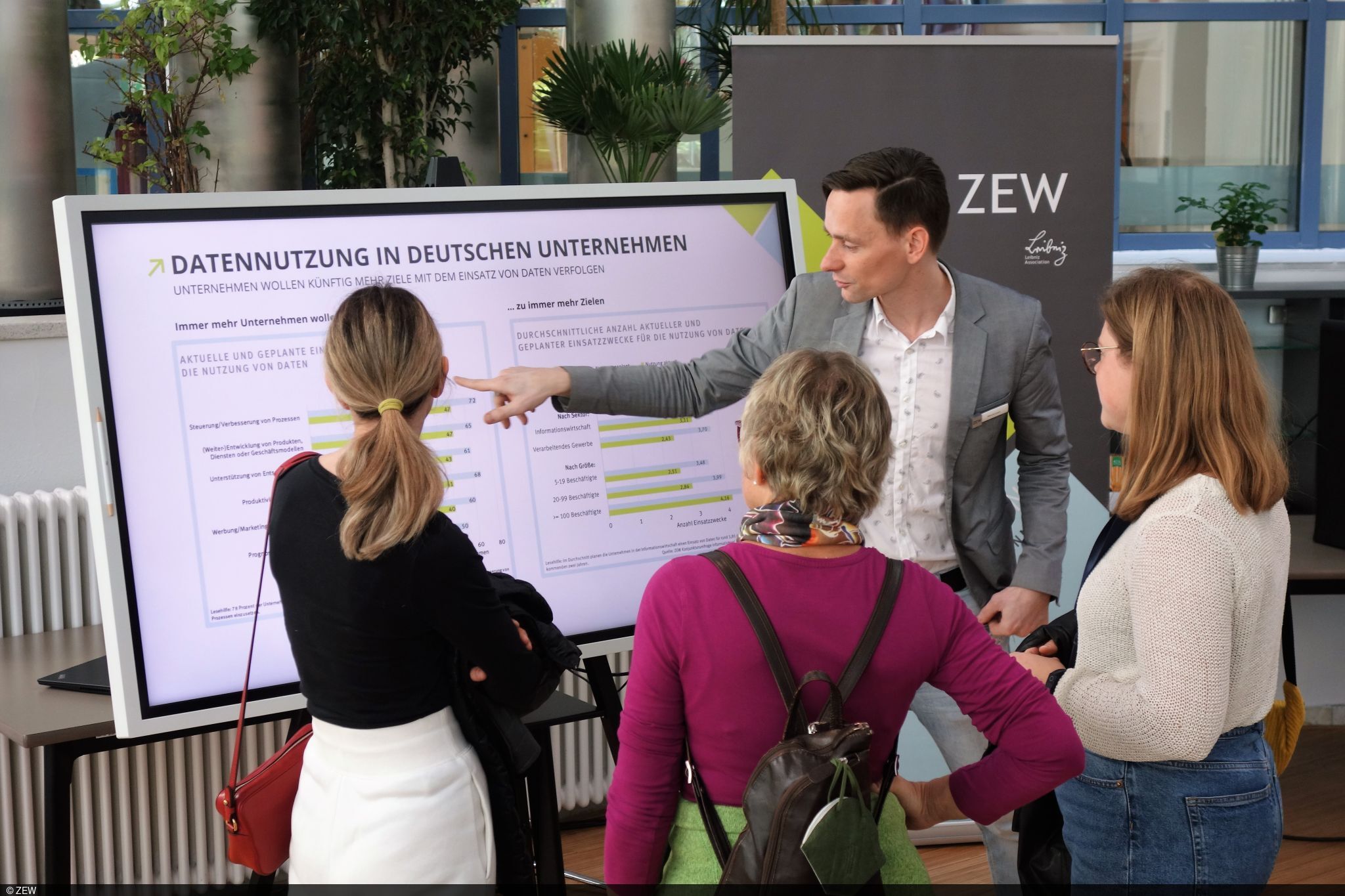 ZEW-Kollege Manuel Lauer vor einem Bildschirm, drei Frauen hören ihm zu