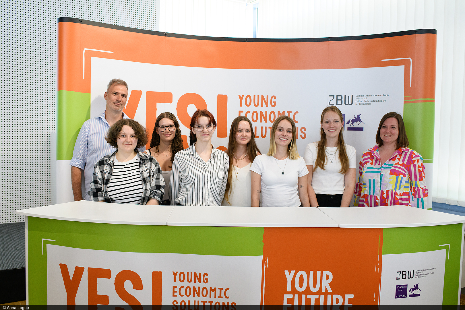 Pupils stand behind a desk with a "YES! Economic Solutions" banner.