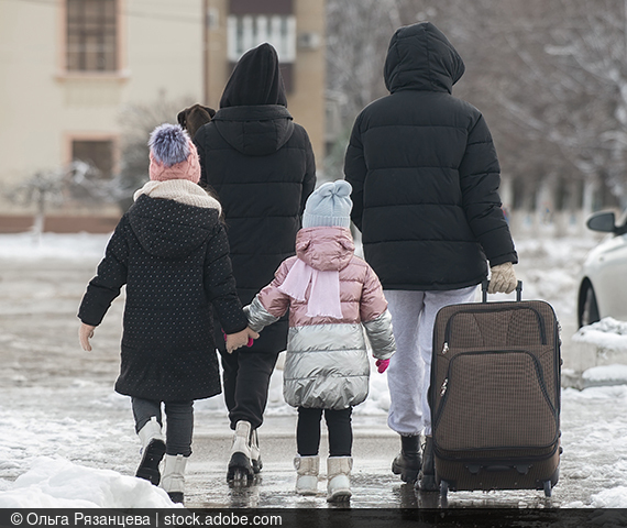 Foto einer vierköpfigen Familie unterwegs mit einem Koffer.