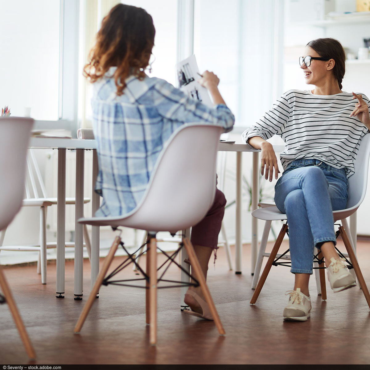 Zwei Frauen bei der Arbeit in einer Agentur mit Designmöbeln in entspannter Sitzhaltung