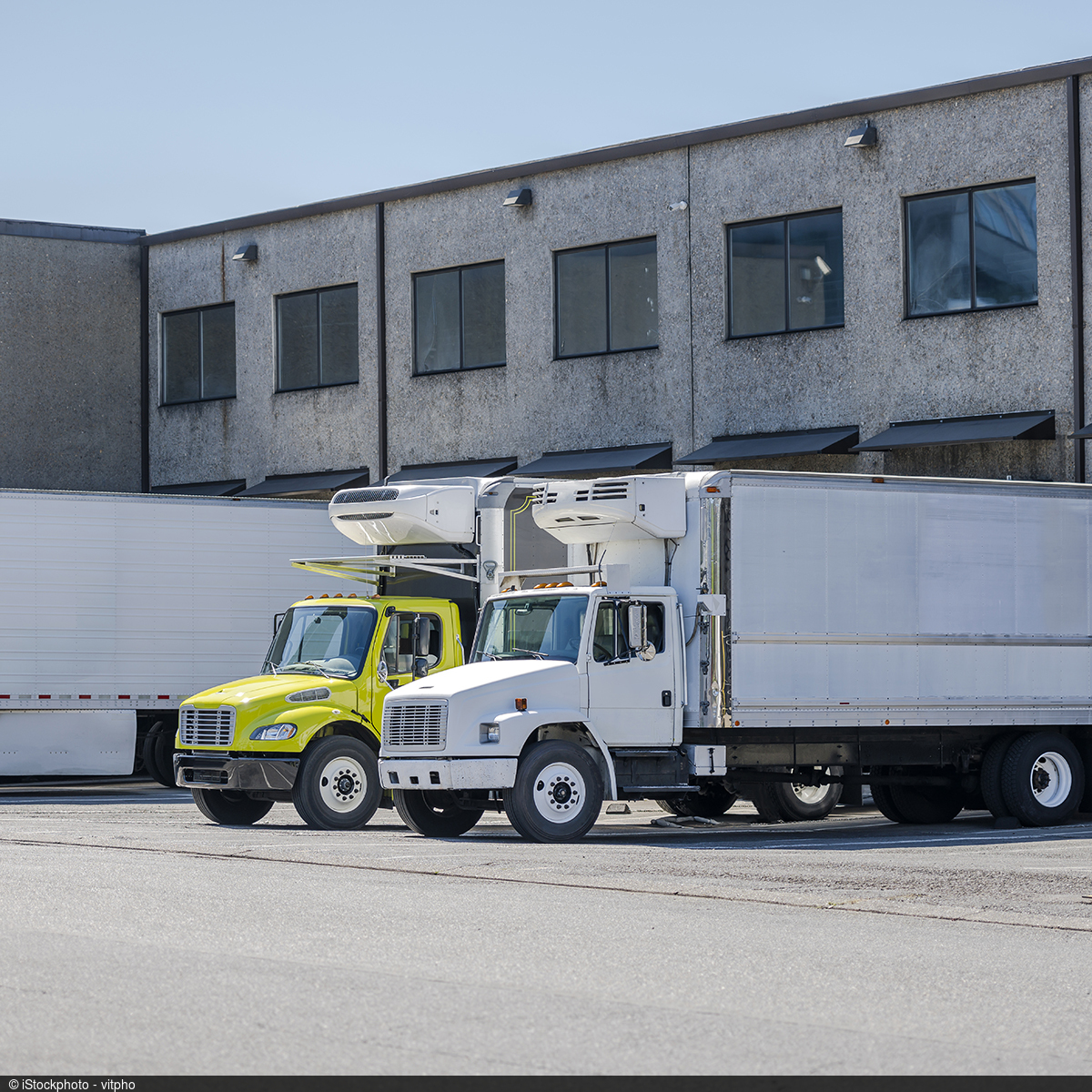 Picture of a large warehouse with truck ramps in front of which several trucks are docked