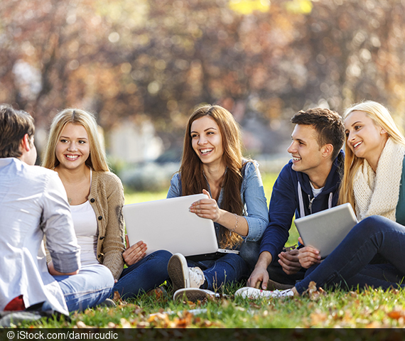 Fünf junge Erwachsene sitzen auf dem Boden zusammen und kommunizieren miteinander.